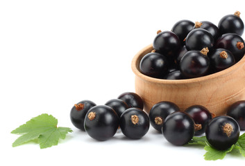black currant in wooden bowl with green leaf isolated on white background