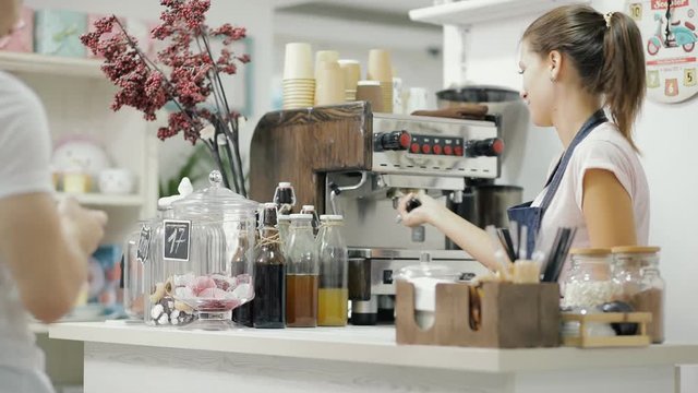 Female barista working, she make drink for a client on a coffee machine