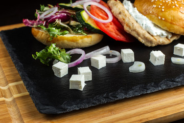 Open hamburger lies on the slate tile.