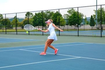 Fototapeta premium Young woman is playing tennis on the tennis court
