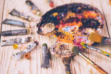 Oil paints and paint brushes on a palette close up.