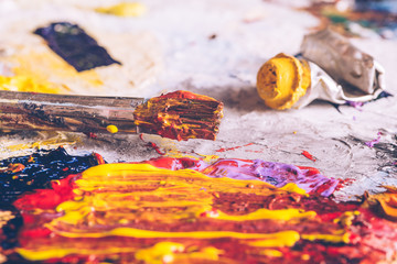 Oil paints and paint brushes on a palette close up.
