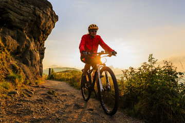 Obraz premium Mountain biking women riding on bike in autumn mountains forest landscape. Woman cycling MTB flow trail track. Outdoor sport activity.