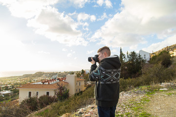 Travel, vacation, photographer and hitchhiker concept - traveler man photographed mountains and town