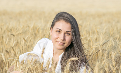 Portrait of a beautiful sexy female smiling in wheat field at warm summer day