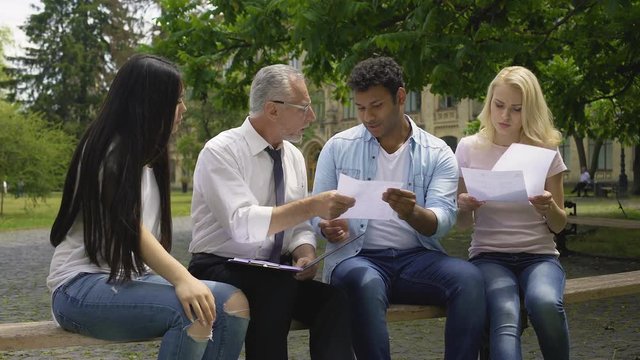 Multi-ethnic students giving thesis plans to their teacher, higher education