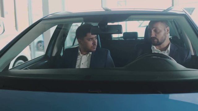 Manager and businessman are talking inside modern automobile in car dealership