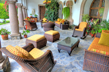 Outdoor sitting room with chairs, seats, couches and tables, decorated with plants, arches and old...