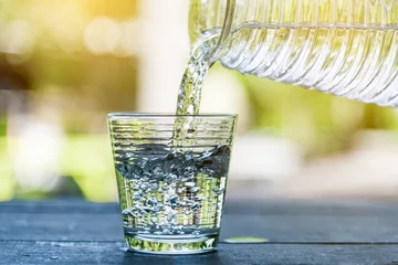 Sierkussen Giet drinkwater in het glas. Giet koel drinkwater. IJs in glas en drinkwater. Schoon drinkwater. © vizaphoto