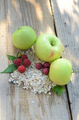 Green apples next to the raspberry with the leaves of gooseberries and a bunch of oatmeal