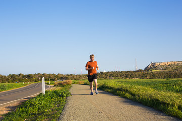 Man running outdoor sprinting for success. Male fitness runner sport athlete in sprint at great speed in beautiful landscape.