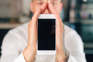 Man is holding white smartphone. Smart home concept.