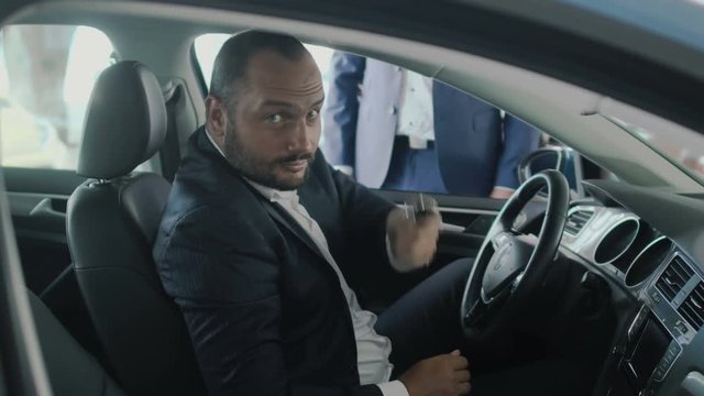 Happy owner of new car demonstrates keys in the car's cabin