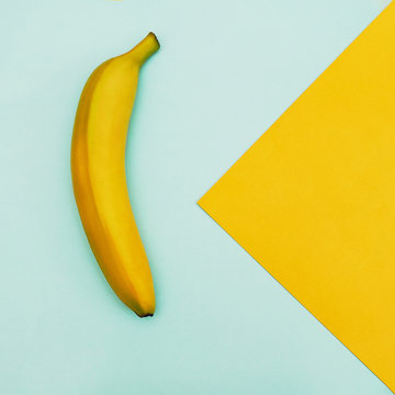 Fruit in flat lay Ripe yellow banana is lying on two-tone background Top view Trendy colorful flat lay photo of banana with space for text