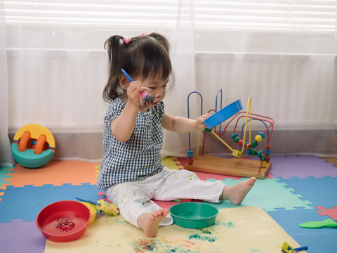 Baby girl play finger paints at home