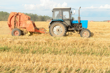 Fototapeta na wymiar Special machines for harvesting form round bales of hay.
