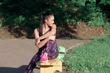 Naklejka premium Concept of sport and lifestyle - young woman having a rest after playing sports smiling sitting on a bench, outdoors