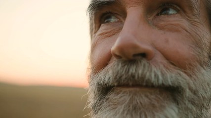 Close up portrait of senior man with beard looking to the camera in the golden field background. - Powered by Adobe