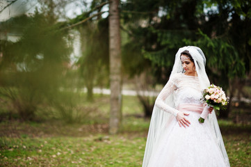 Portrait of a pretty bride posing in the park with a bouquet on a wedding day.