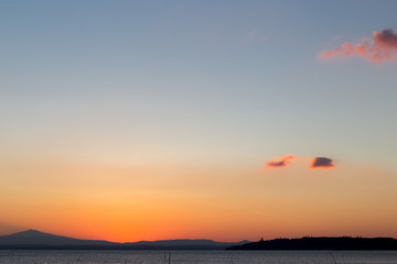 The end of sunset and the beginning of dusk on a lake, with big sky and red clouds
