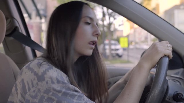 Young Woman Drives Carefully Through City, Looks Both Ways At Intersection