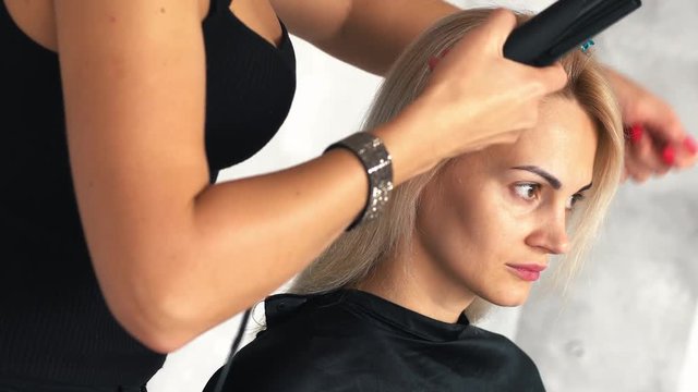 hairdresser makes the basal volume using a corrugated plaque in beauty salon