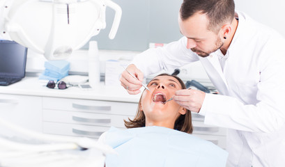 Obraz premium Dentist is treating patient which is sitting in dental chair in clinic