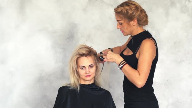 hairdresser makes the basal volume using a corrugated plaque in beauty salon