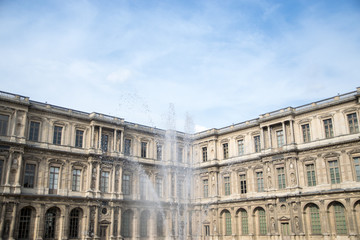 Naklejka premium Inner courtyard and exterior of The Louvre Museum with walking tourists in a summer day
