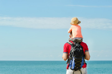 Father and son on their shoulders stand on the sea shore, rear view