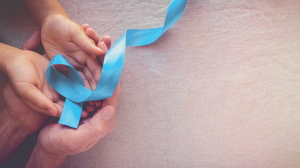 Adult and child hands holding Light blue, sky blue ribbons, toning background, Prostate Cancer...