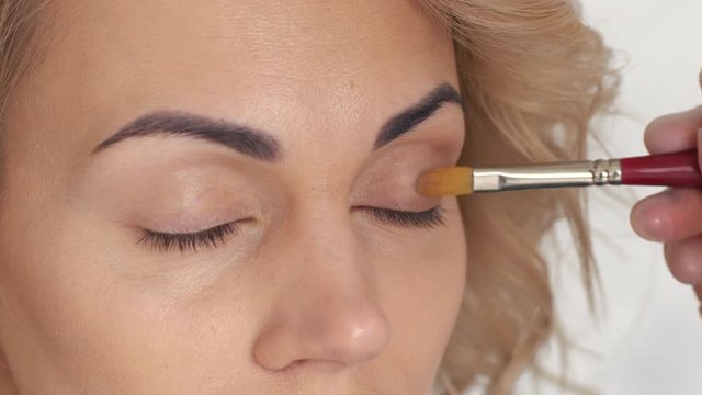 Make-up artist puts eye shadow in the beauty salon, close-up