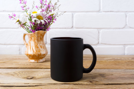 Black coffee mug mockup with chamomile and purple flowers in golden pitcher