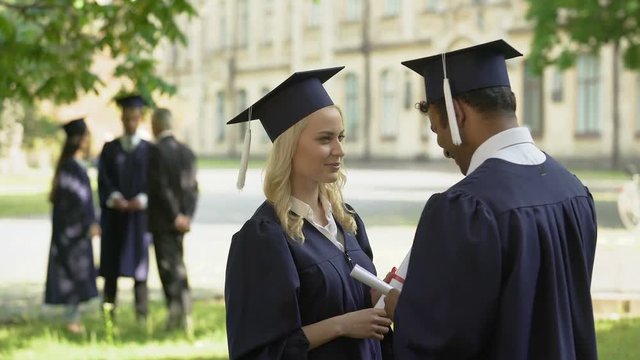 Male, female graduates talking after ceremony, university education, adult life
