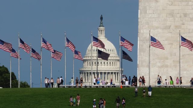 WASHINGTON, D.C. - Circa August, 2017 - A daytime long establishing shot of tourists visiting the Washington Monument with the Capitol Dome in the distance. Shot in 5K.  	