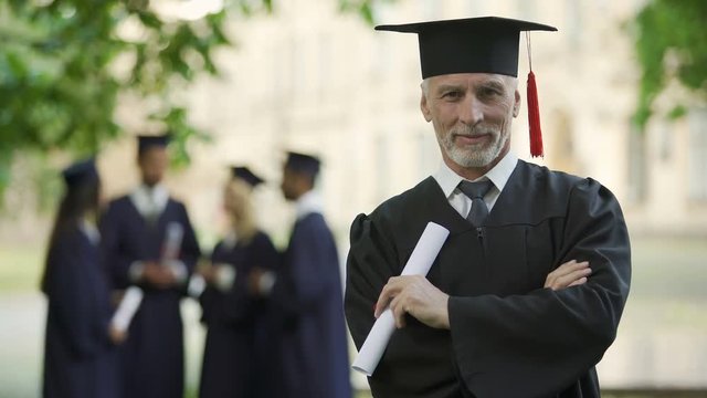 Aged man in graduation outfit, professor obtaining new degree, academic career