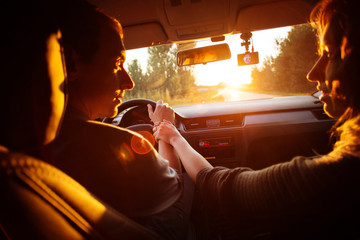 Couple driving car on way to sunset