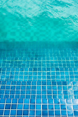 Blue mosaic tiled steps in green swimming pool