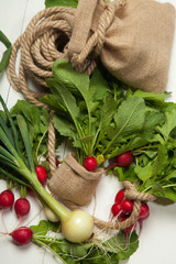 Fresh radishes and onions on a white wooden background