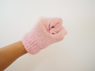 Left hand wearing pale pink scrubbing glove, on white background, fist 