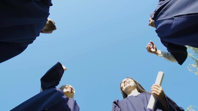 University graduates tossing up their square caps student tradition, bottom view