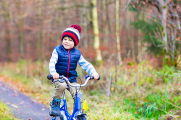 Little kid boy with bicycle in autumn forest