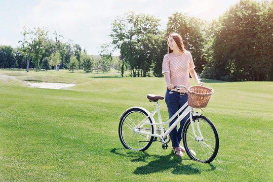 Cheerful woman with vintage bicycle on lawn on sunny day