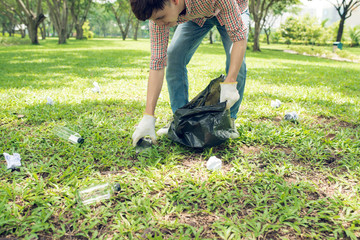 Asian man picking up plastic household waste in park