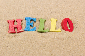 Word hello of colored wooden letters on sandy beach