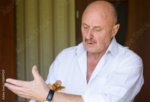 Portrait of a mature stylish man in white shirt , tasting perfume. Elderly metrosexual gay man spraying fragrance perfume. The man is going to the dressing ... Portrait of a mature stylish man in white shirt , tasting perfume ...
