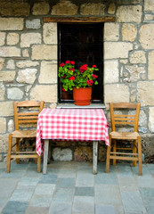 Fototapeta na wymiar view of exterior house with old chairs and table on stone street.Greece