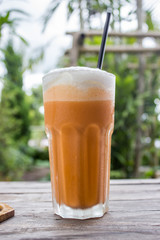 Thai tea frappe with white cream or steam milk on wood table. Ready to eat. In the coffee shop.