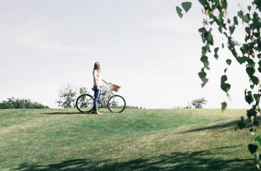 Woman with vintage bicycle on lawn looking into the distance