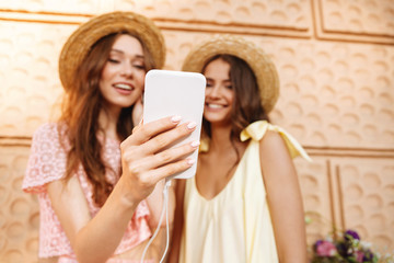 Happy ladies standing outdoors using phone